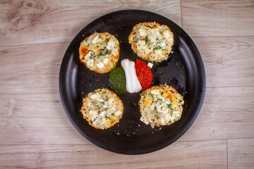 Cheese garlic bread with green herbs on plate over wooden background