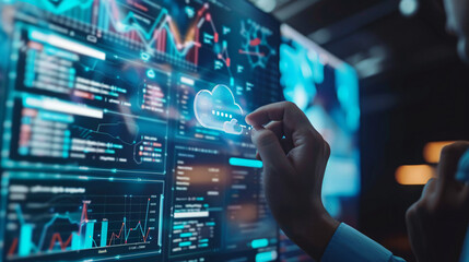 Close-up of hands interacting with a digital screen displaying various data analytics, charts, and cloud computing elements in a modern workspace.