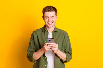 Photo of handsome nice man wear stylish khaki clothes use modern device isolated on vibrant yellow...