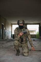 Military mission. Soldier in uniform with drone controller inside abandoned building