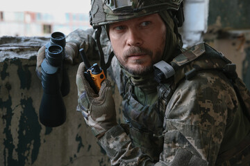 Fototapeta premium Military mission. Soldier in uniform with binoculars inside abandoned building