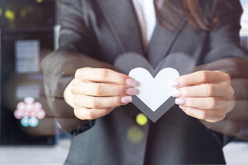 Woman in business suit holding a paper heart .