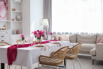 Beautiful table setting with flowers and rattan chairs in dining room