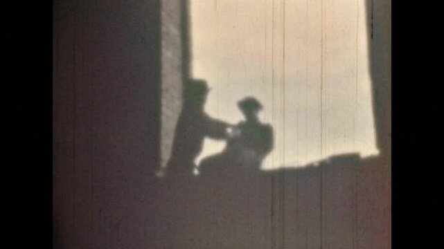 Silhouettes, man throwing enemy out of window. Aggressive fight between men in hats. Cowboys sort things out in fist fight. Struggle in wild west style. Vintage color film. Retro battle combat archive