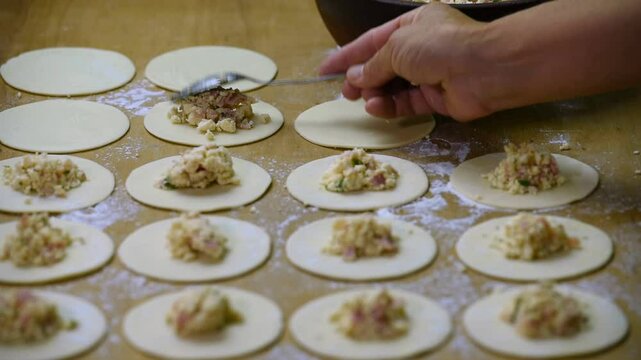 hands working and filling fresh pasta sorrentino ravioli with ricotta and fresh dough on kitchen counter