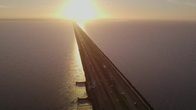 Aerial view of sunset over dam and lake with road, Afsluitdijk, Netherlands.