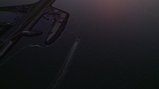Aerial view of tranquil dam and boat at sunset on Afsluitdijk, Friesland, Netherlands.