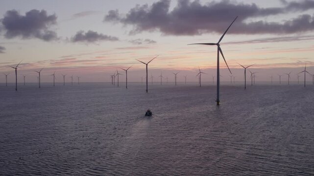 Aerial view of offshore windpark with boat and wind turbines at sunrise, Ijsselmeer, Netherlands.