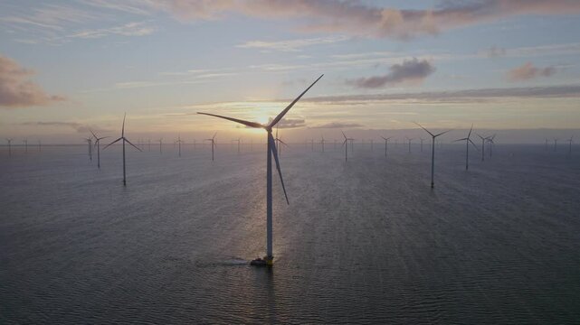 Aerial view of offshore windpark with boat and wind turbines at sunrise, Afsluitdijk, Netherlands.