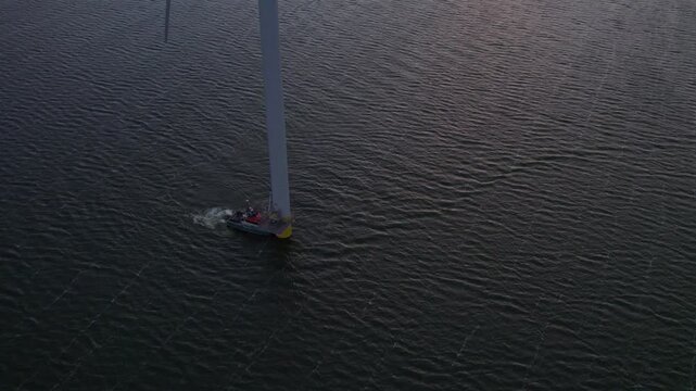 Aerial view of offshore wind farm with boat and wind turbines on the lake, Afsluitdijk, Friesland, Netherlands.