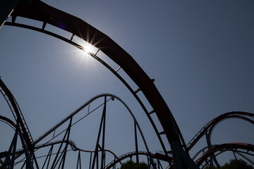 Roller Coaster silhouetted against a blue sky. Theme park track background