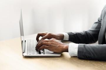 A businessman types on a laptop while sitting at a desk.