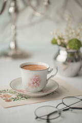 A cup of coffee on the table, flowers and a book