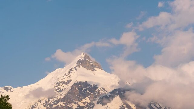 4K Time-lapse shot of orange clouds above the snowy Ghepan peak as seen from Khangsar village in Lahaul, Himachal Pradesh, India. Clouds roll above the mountain peak during the sunset. Natural evening
