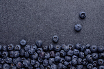 Blueberries are scattered over a textured blue background that copies the space