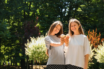 Fototapeta premium Two beautiful twin sisters with ice cream in park