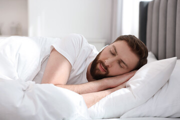 Handsome young man sleeping in bed at morning