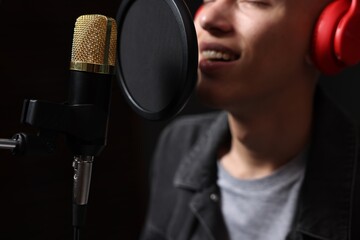 Vocalist singing into microphone in professional record studio, closeup