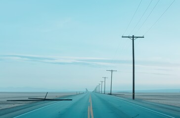 Long empty road with telephone poles under a clear blue sky in a desolate desert landscape, evoking solitude and tranquility.