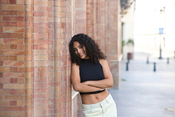 beautiful Latin woman with black eyes and brunette with long curly hair leaning on her side with...
