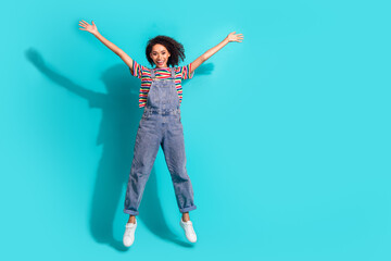 Photo of positive girl jump raise hands up isolated cyan color background