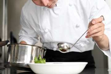 料理を皿に盛る若いアジア人の男性調理師