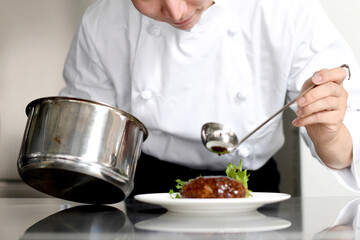 料理を皿に盛る若いアジア人の男性調理師