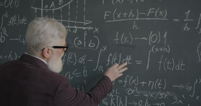 Experienced college professor thinking about formula underlining equation focused on maths study in classroom. Academic education and people concept.