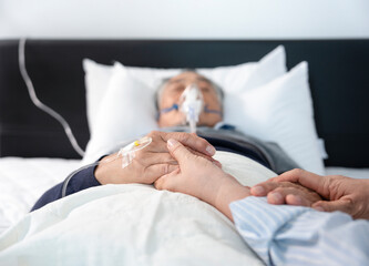 scene of a wife holding hands hopeless senior male patient who having oxygen and keep intravascular...