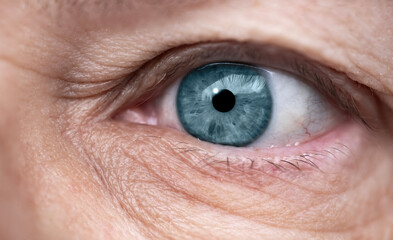 close-up mature female eye looking to side, concept of patient care, wrinkles around eyes, upper...