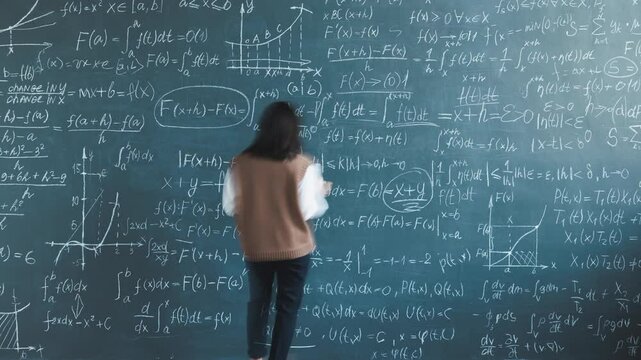 Zoom-in time lapse of young lady researcher solving equations writing on chalkboard in university laboratory. Science development and intelligent person concept.