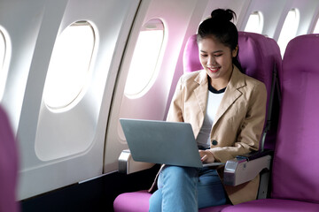 young businesswoman uses laptop while flying airplane for work