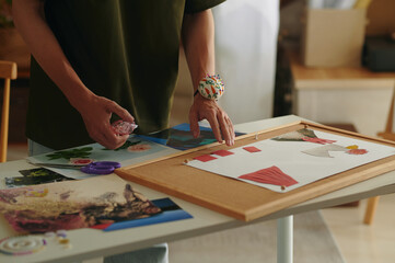 Close-up of designer making collage with new collection from photos and fashion details