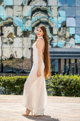 Naklejka premium Portrait of a young beautiful blonde girl in a white summer dress with open shoulders