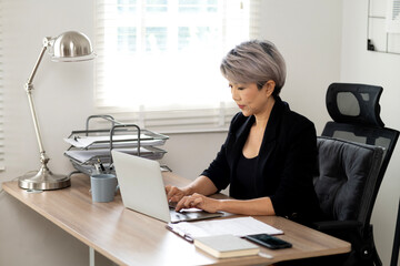 senior businesswoman is sitting and typing information