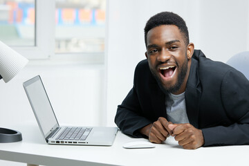 Surprised businessman in office suit reacting to unexpected news on laptop at work desk