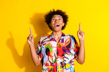 Portrait of nice young man indicate fingers up empty space wear shirt isolated on vivid yellow color background