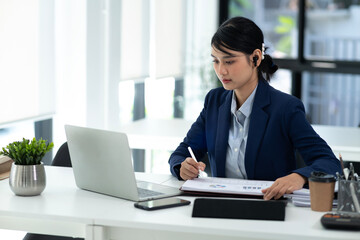 young business woman is writing notes on the data she is viewing on the notebook