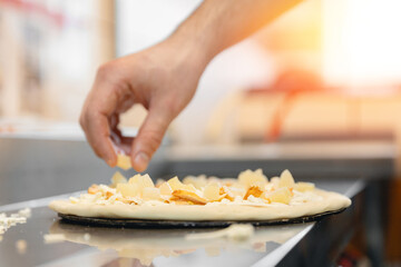 Pizzamaker worker preparing fresh food pizza adds toppings with mozzarella cheese, top view. Business pizzeria concept.