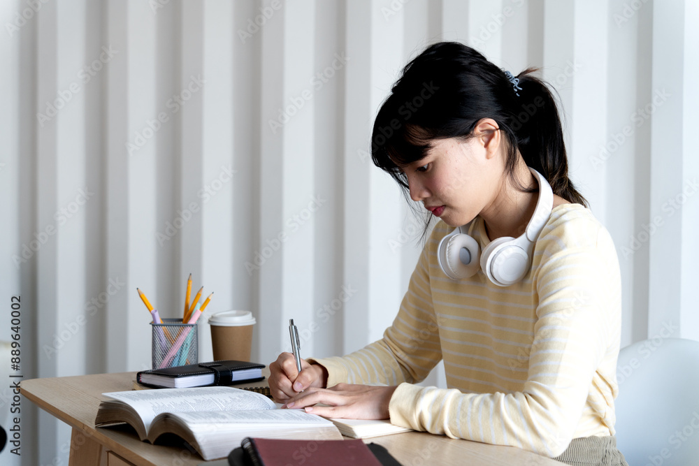 Poster teenage woman is sitting on her home desk reading a book