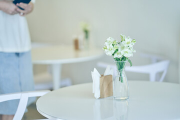 White flowers in a vase on a table on a white background. flower arrangement, space for copying. The unfocused woman next to me. High quality photo