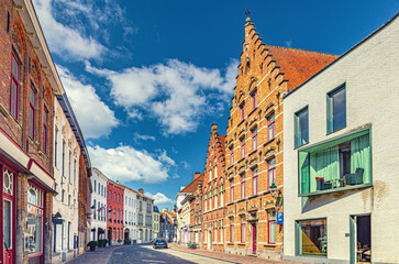 Fototapeta premium Bruges cityscape with paving stone road street, buildings and houses with brick walls and gables in Brugge city historic centre, Bruges old town Sint-Anna quarter district, Flemish Region, Belgium