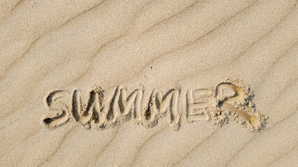 Word 'SUMMER' written in the sand, symbolizing vacation and relaxation during the summer holiday season