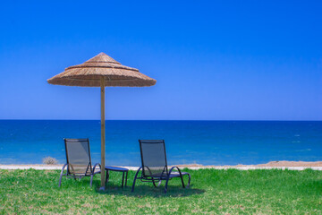 Einsamer Strand mit Sonnenschirm und Liegestühlen am Meer