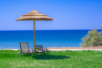 Einsamer Strand mit Sonnenschirm und Liegestühlen am Meer