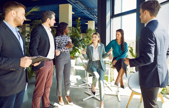 Businesswoman conducting a team meeting or work presentation for a group of colleagues in the office. Communication skills and collaboration in a professional setting among business people.