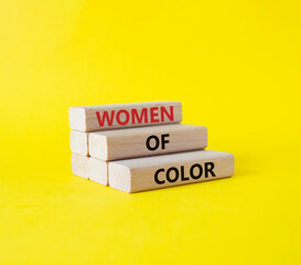 Women of color symbol. Concept words Women of color on wooden blocks. Beautiful yellow background. Business and Women of color concept. Copy space.