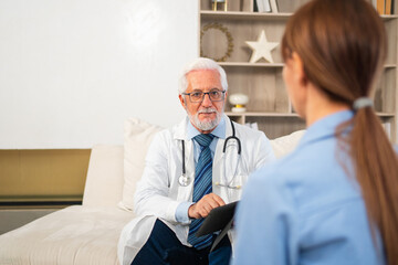 Senior man doctor examining young woman in doctor office clinic or at home. Girl patient and doctor have consultation in hospital room. Medicine healthcare medical checkup. Visit to doctor