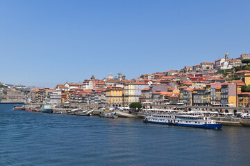 Obraz premium A vibrant view of Porto's colorful riverside buildings along the Douro River, showcasing the historic architecture and lively atmosphere of this UNESCO World Heritage city. Porto - Portugal