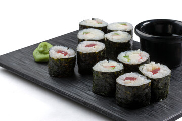 Sushi variado en tabla negra sobre fondo blanco. Assorted sushi on black board on white background.